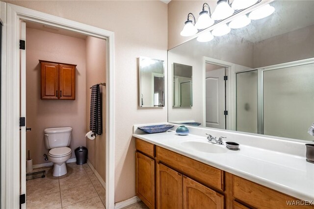 bathroom with baseboards, toilet, tile patterned floors, vanity, and a shower stall