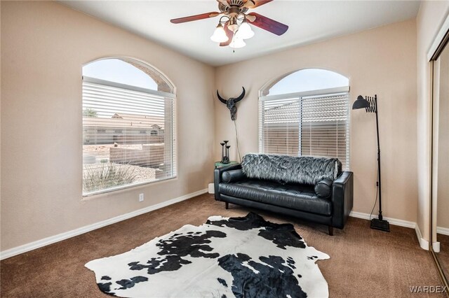 living area with a ceiling fan, carpet flooring, plenty of natural light, and baseboards