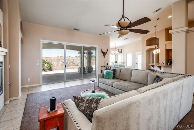 living area with ceiling fan with notable chandelier, light tile patterned flooring, visible vents, and baseboards