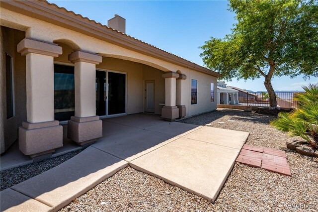 rear view of house with stucco siding, a tiled roof, fence, and a patio