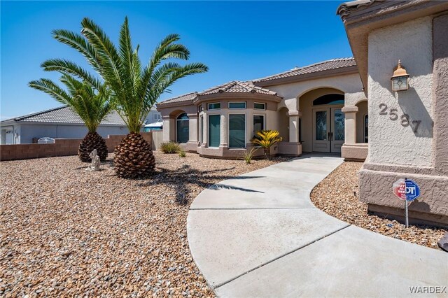 exterior space with a tiled roof, french doors, and stucco siding