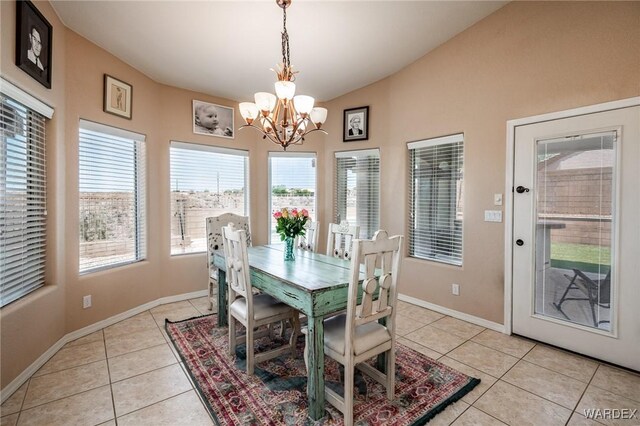 dining room with light tile patterned floors, baseboards, vaulted ceiling, and a notable chandelier