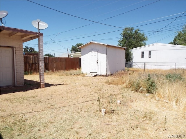 view of yard featuring an outdoor structure, fence, and a shed
