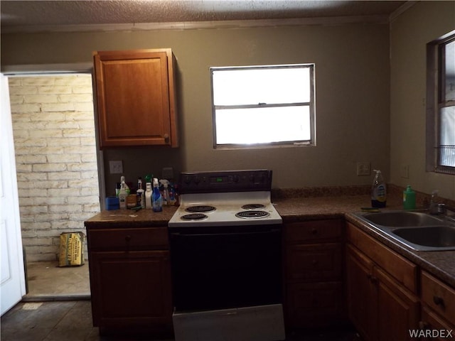 kitchen with electric range, dark countertops, brick wall, a textured ceiling, and a sink
