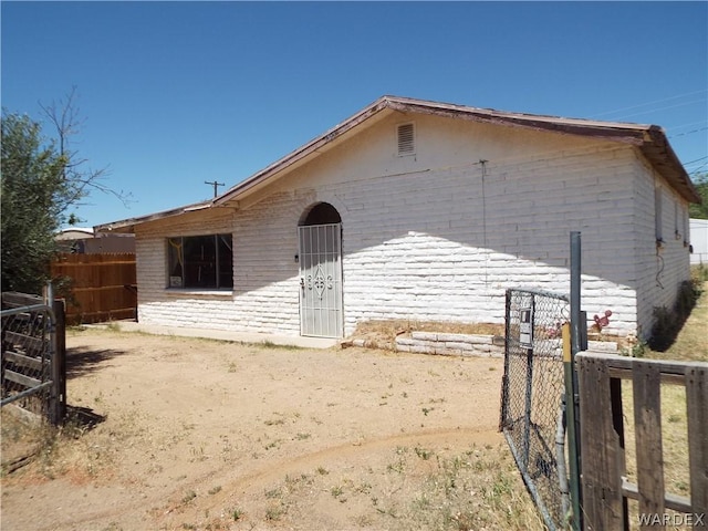 rear view of house featuring fence and brick siding