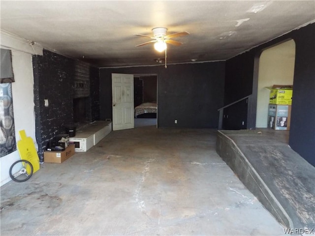 unfurnished living room with a ceiling fan, arched walkways, and concrete floors