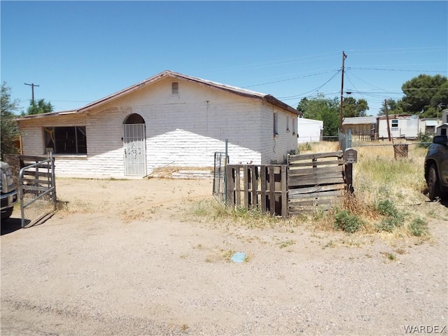 view of property exterior featuring brick siding and fence