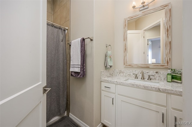 bathroom featuring curtained shower, vanity, and baseboards