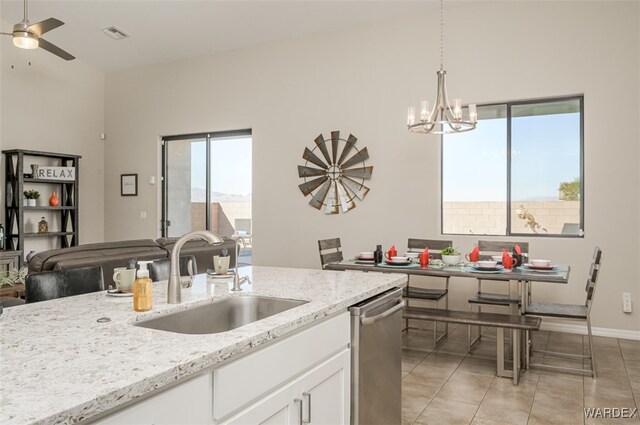 kitchen featuring light stone counters, white cabinetry, a sink, and stainless steel dishwasher