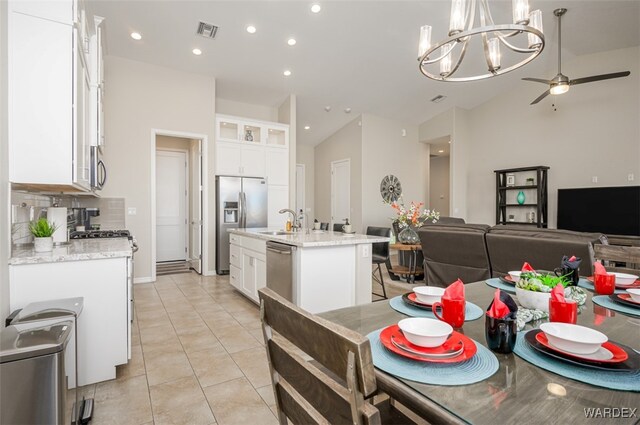 kitchen with stainless steel appliances, visible vents, white cabinets, a center island with sink, and pendant lighting