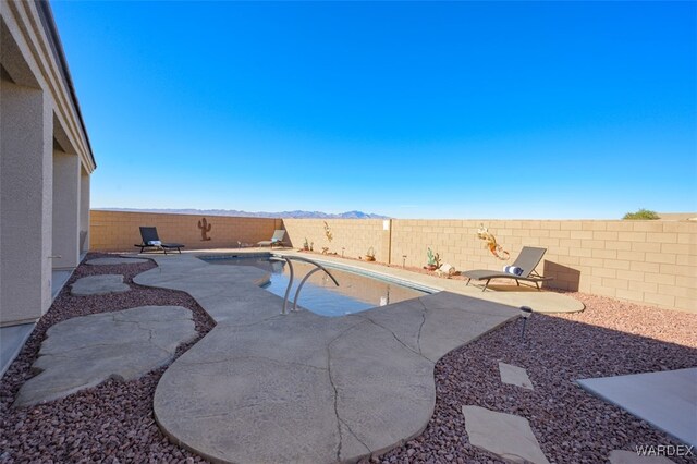 view of swimming pool featuring a patio, a fenced backyard, and a mountain view