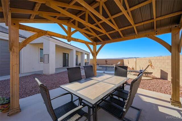 view of patio with a gazebo, outdoor dining space, and fence