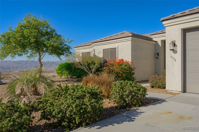 view of home's exterior with a garage, a mountain view, and stucco siding