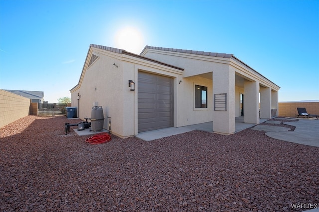 view of property exterior featuring a patio area, an attached garage, a fenced backyard, and stucco siding