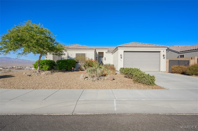 view of front of house with a garage, concrete driveway, a mountain view, and stucco siding