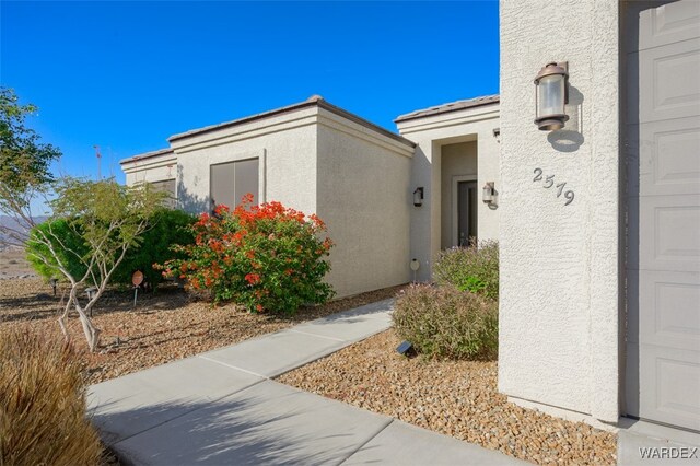 doorway to property with a garage and stucco siding