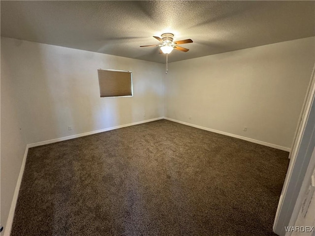 spare room with a ceiling fan, dark colored carpet, a textured ceiling, and baseboards