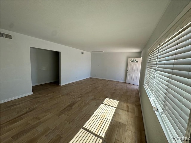 unfurnished living room featuring wood finished floors, visible vents, and baseboards