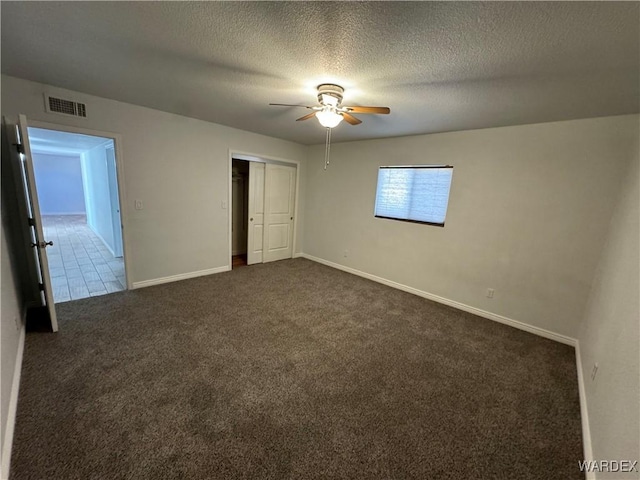 unfurnished bedroom featuring a textured ceiling, visible vents, baseboards, a closet, and dark carpet