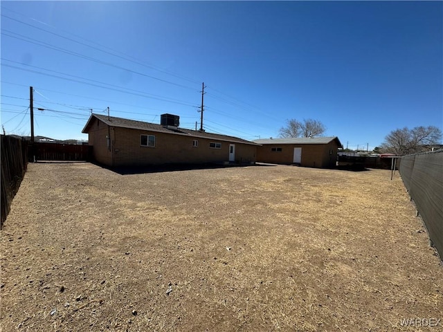 back of house featuring a fenced backyard and central AC