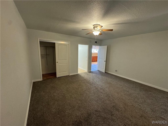 unfurnished bedroom with baseboards, a closet, dark carpet, and a textured ceiling