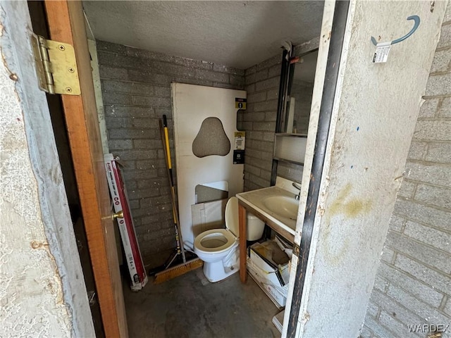 bathroom featuring toilet, a sink, a textured ceiling, and concrete flooring