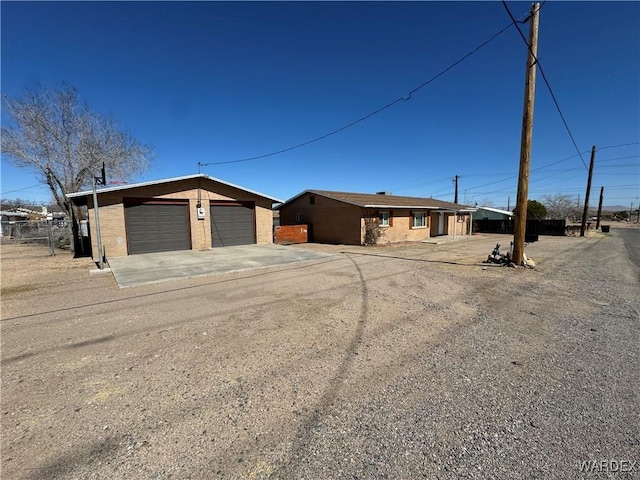 view of front facade featuring an outbuilding, brick siding, fence, and a garage