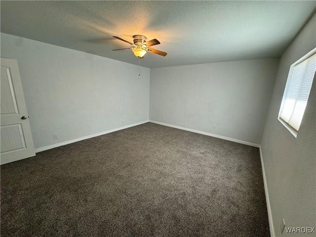 empty room featuring dark colored carpet, a textured ceiling, and baseboards