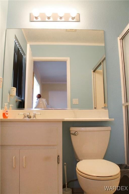 bathroom featuring toilet, a shower with door, and vanity