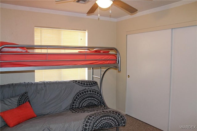 bedroom with carpet floors, ornamental molding, a closet, and a ceiling fan