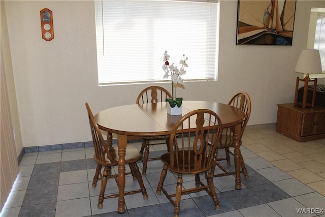 dining space featuring dark tile patterned floors and baseboards