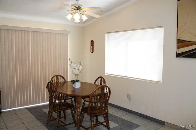 dining room featuring lofted ceiling, dark tile patterned flooring, a ceiling fan, baseboards, and crown molding