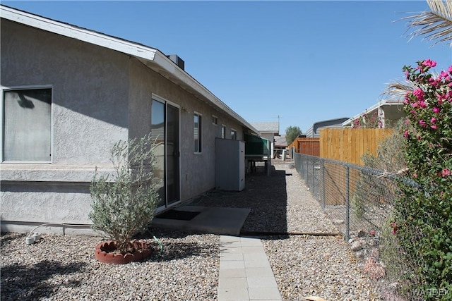 view of side of home with fence and stucco siding