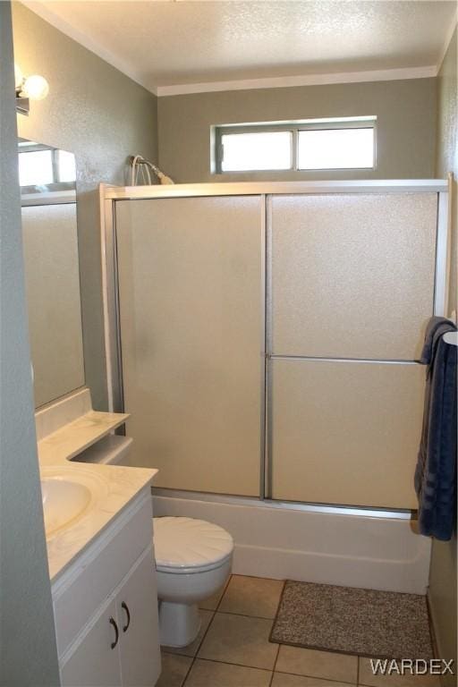 bathroom with a textured ceiling, tile patterned flooring, toilet, shower / bath combination with glass door, and vanity