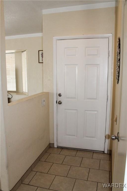 doorway with tile patterned flooring and ornamental molding