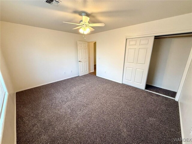 unfurnished bedroom with dark colored carpet, a closet, visible vents, ceiling fan, and baseboards