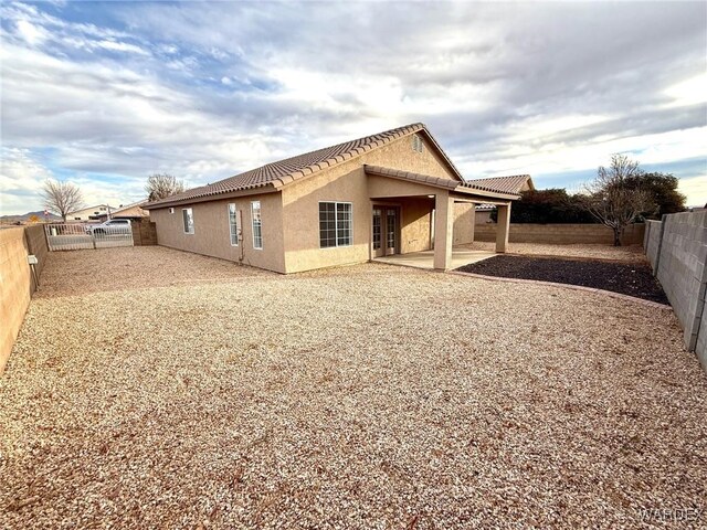 rear view of house featuring a patio area, a fenced backyard, a tiled roof, and stucco siding