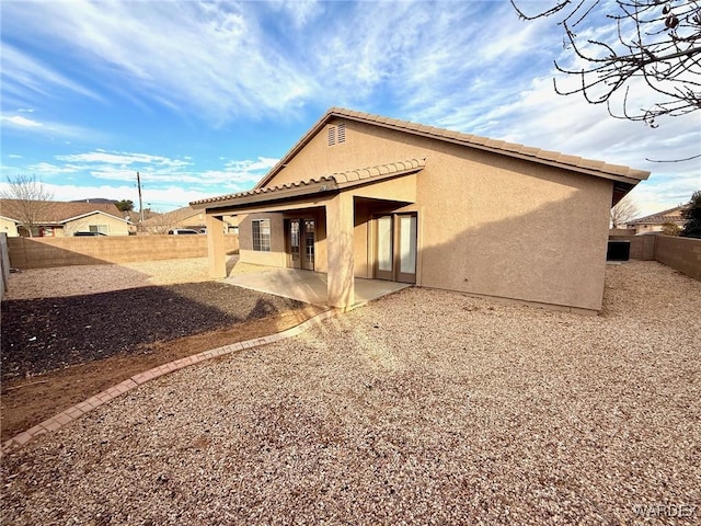 rear view of property featuring a patio area, a fenced backyard, a tiled roof, and stucco siding