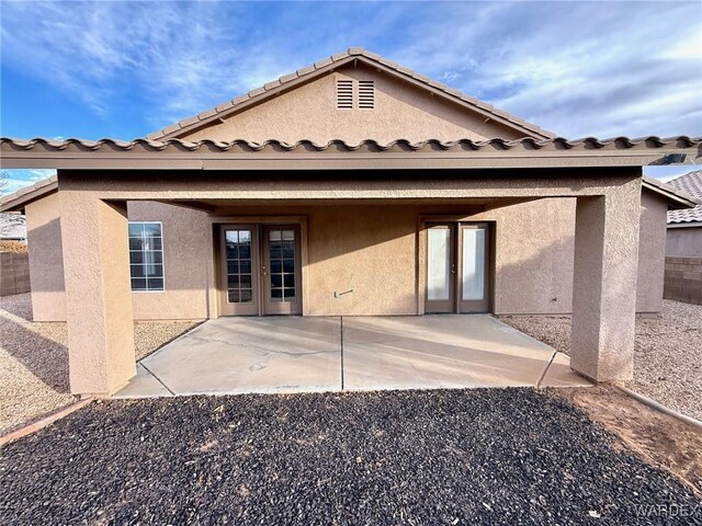 back of property featuring a patio area, a tile roof, french doors, and stucco siding