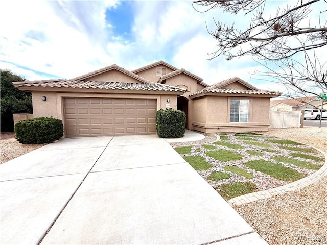 mediterranean / spanish home with a garage, a tiled roof, concrete driveway, and stucco siding