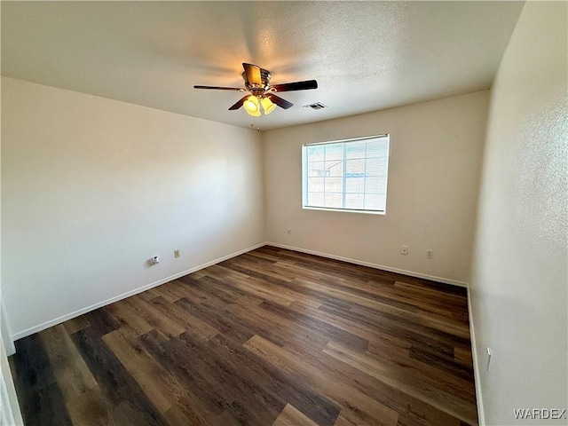 empty room featuring baseboards, dark wood-type flooring, visible vents, and a ceiling fan