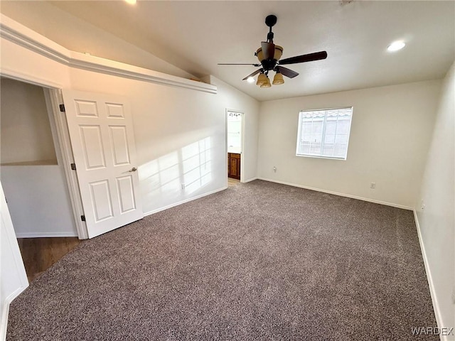 interior space featuring lofted ceiling, baseboards, dark carpet, and ceiling fan