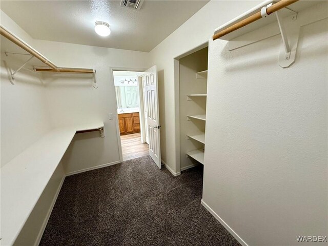 walk in closet featuring visible vents and dark carpet