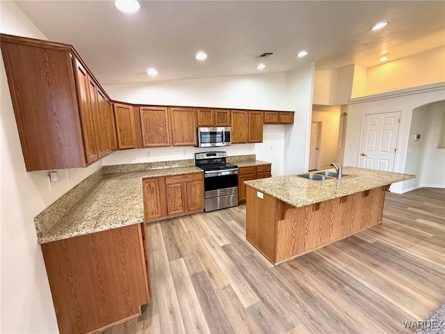 kitchen featuring a center island with sink, visible vents, appliances with stainless steel finishes, brown cabinets, and a sink