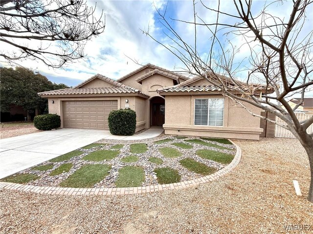 mediterranean / spanish house featuring an attached garage, a tile roof, concrete driveway, and stucco siding