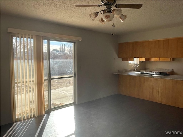 kitchen featuring a textured ceiling, concrete floors, a sink, a ceiling fan, and light countertops