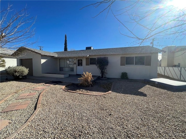 back of property with an attached garage, fence, and stucco siding