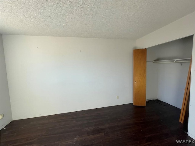 unfurnished bedroom with dark wood-style floors, a textured ceiling, and a closet