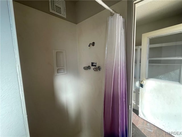 bathroom featuring a shower with shower curtain, wood finished floors, and visible vents