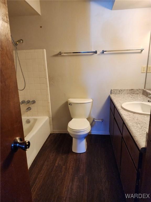 bathroom featuring toilet, shower / bath combination, wood finished floors, vanity, and baseboards